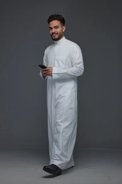Saudi Man in Traditional Thobe Using Smartphone Studio