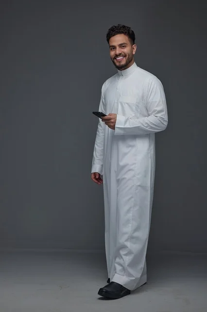 Saudi Man in Traditional Thobe Using Smartphone