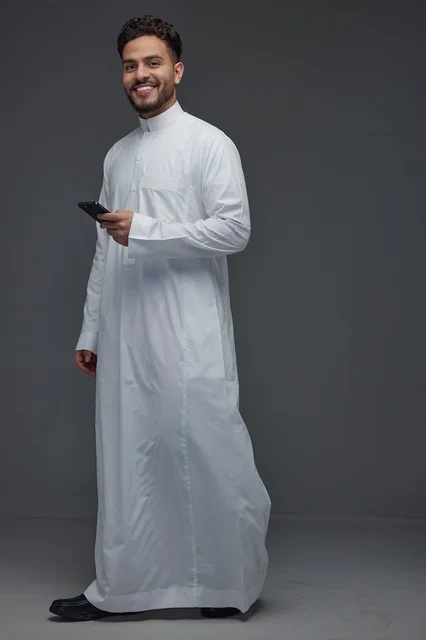 رجل سعودي بالثوب التقليدي يستخدم الهاتف الذكي