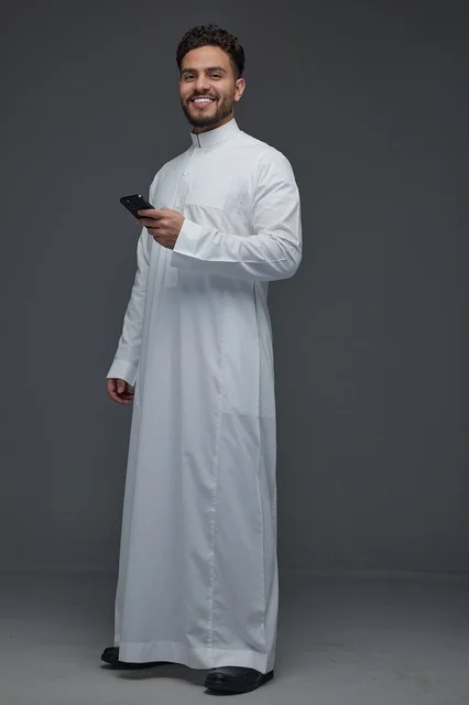 رجل سعودي بالثوب التقليدي يستخدم الهاتف الذكي