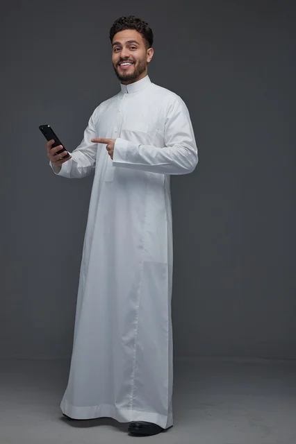 رجل سعودي بالثوب التقليدي يشير إلى هاتف ذكي