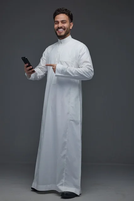 رجل سعودي يشير إلى هاتف ذكي بالثوب التقليدي