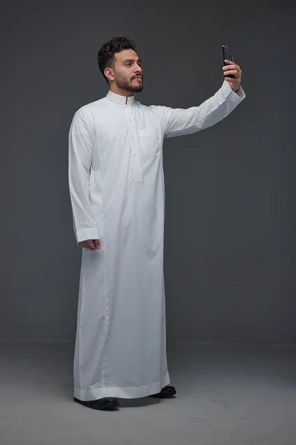 رجل سعودي بالثوب التقليدي يلتقط صورة سيلفي بالجوال رجل سعودي بالثوب التقليدي يلتقط صورة سيلفي بالجوال