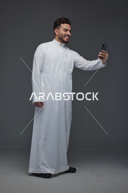 رجل سعودي بالثوب الأبيض يلتقط سيلفي في الاستوديو