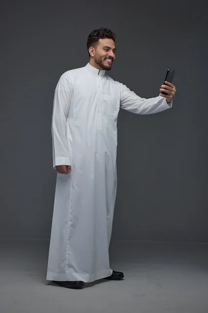 رجل سعودي بالثوب الأبيض يلتقط سيلفي في الاستوديو