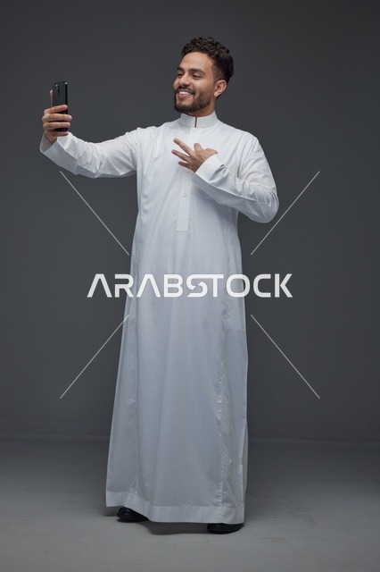 رجل سعودي بالثوب التقليدي يلتقط صورة سيلفي بالجوال