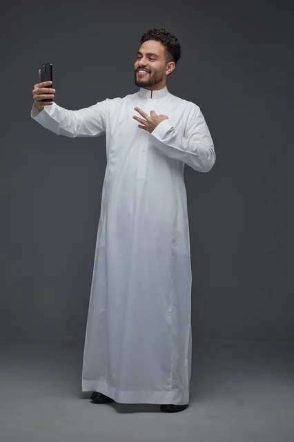 رجل سعودي بالثوب التقليدي يلتقط صورة سيلفي بالجوال