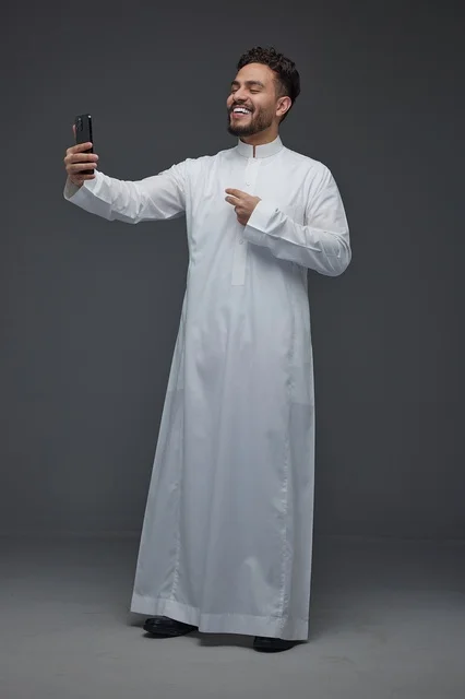 رجل سعودي يرتدي الثوب التقليدي يلتقط سيلفي بالجوال
