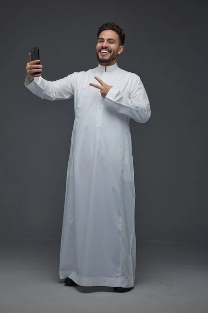 Saudi Man in Traditional Thobe Taking Selfie with Phone