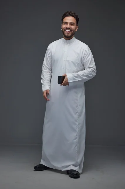 Smiling Saudi Man in Traditional Thobe Holding Smartphone