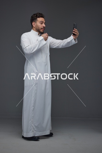 رجل سعودي بالثوب التقليدي يلتقط صورة سيلفي بالجوال
