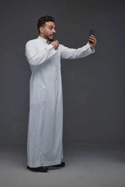 Saudi Man in Thobe Taking Selfie on Gray Background