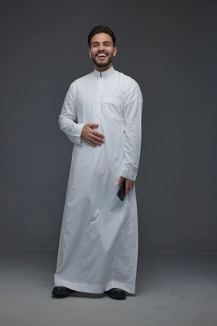 رجل سعودي بالثوب الأبيض التقليدي يحمل هاتف ذكي