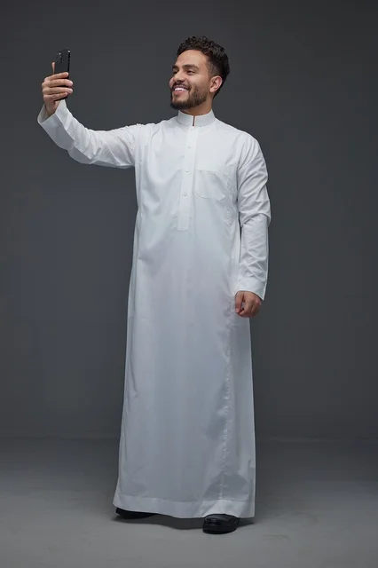 رجل سعودي بالثوب التقليدي يلتقط صورة سيلفي بالجوال