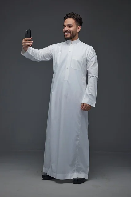 رجل سعودي يرتدي الثوب التقليدي يلتقط سيلفي بالهاتف