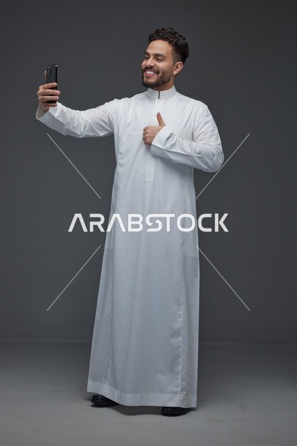رجل سعودي بالثوب التقليدي يلتقط صورة سيلفي