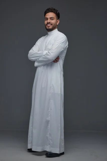 رجل سعودي يرتدي الثوب الأبيض التقليدي في استوديو تصوير