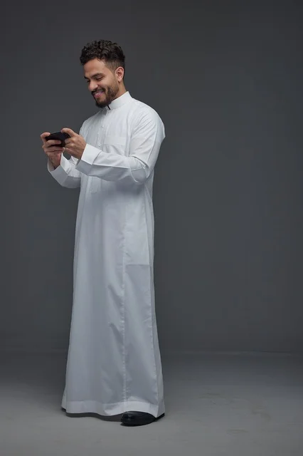 Saudi Man in White Thobe Playing Smartphone Game