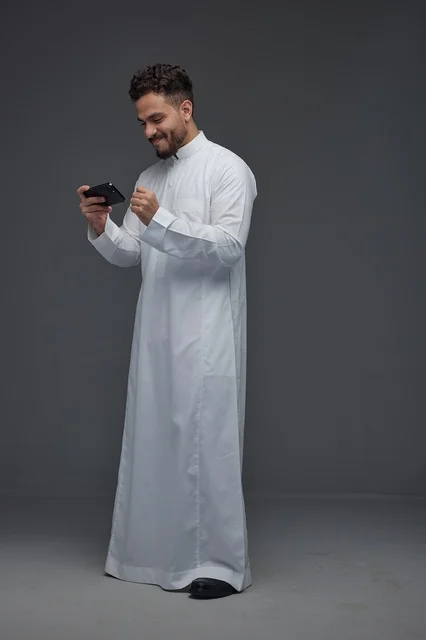 Saudi Man in Thobe Playing Mobile Games on Smartphone