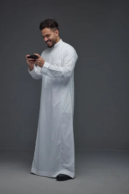 Saudi Man in Traditional Thobe Playing Mobile Game