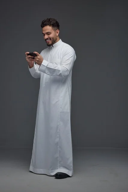 Saudi Man Playing Smartphone Game in Traditional Thobe