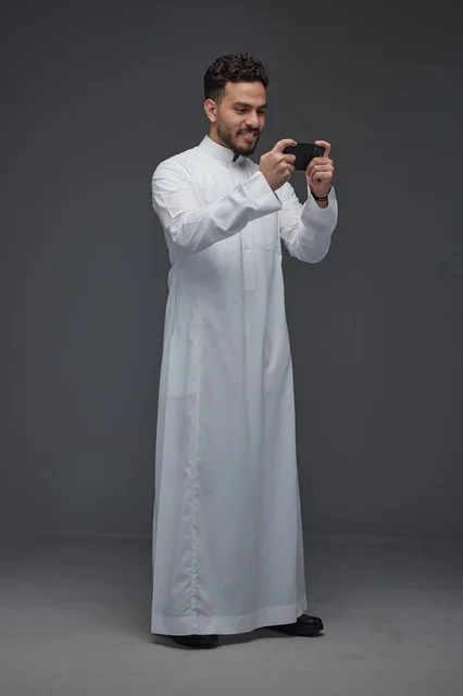 Saudi Man in Traditional Thobe Playing Smartphone Game