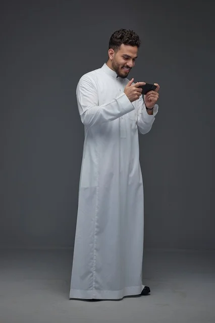 Saudi Man in Traditional Thobe Gaming on Smartphone