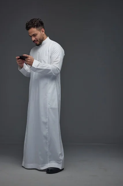 Saudi Man in Thobe Playing on Smartphone