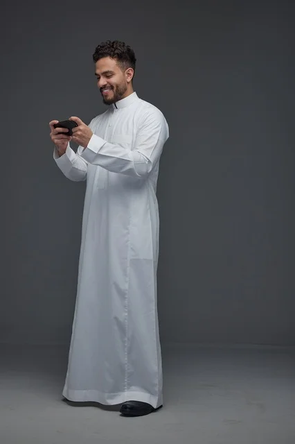 Saudi Man in White Thobe Playing Mobile Games on Phone
