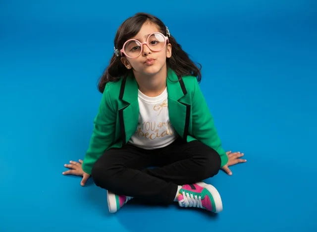 Young Saudi Girl in Green Blazer on Blue Background