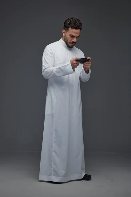 Saudi Man in White Thobe Playing Smartphone Game