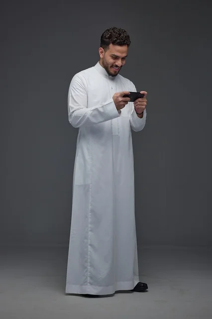 Saudi Man in Traditional Thobe Using Smartphone Studio