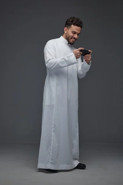 Saudi Man Playing Mobile Game in Traditional Thobe