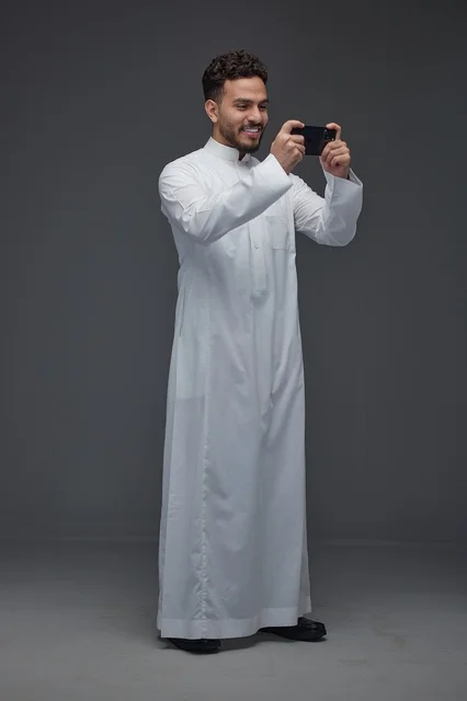 Saudi Man in Traditional Thobe Using Smartphone Studio