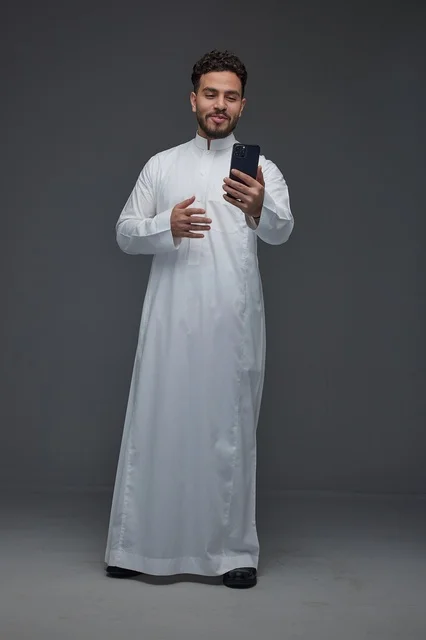 Saudi Man in Traditional Thobe Using Smartphone