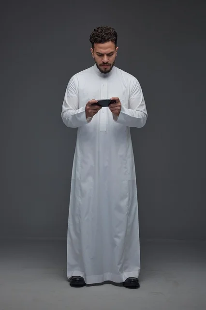 Saudi Man in Traditional Thobe Using Smartphone for Gaming
