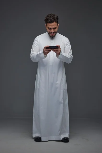 Saudi Man in Traditional Thobe Using Smartphone