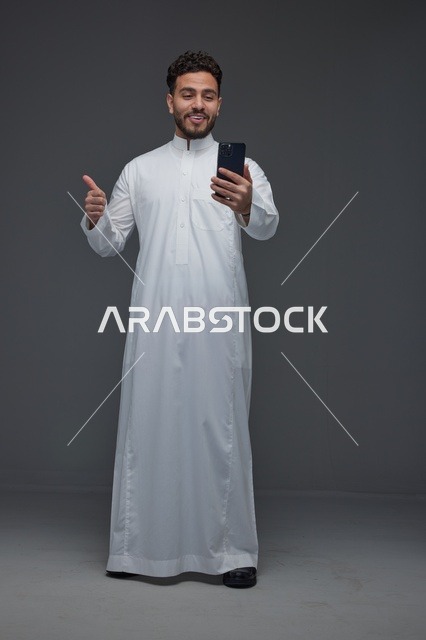 Saudi Man in Thobe Using Smartphone with Thumbs Up