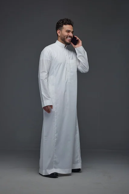 رجل سعودي بالثوب التقليدي يتحدث عبر الهاتف الذكي