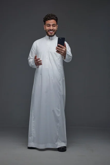 Smiling Saudi Man in Thobe Using Smartphone Studio