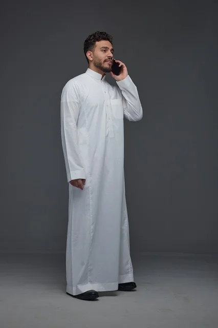 رجل سعودي يرتدي الثوب التقليدي يجري مكالمة هاتفية ذكية