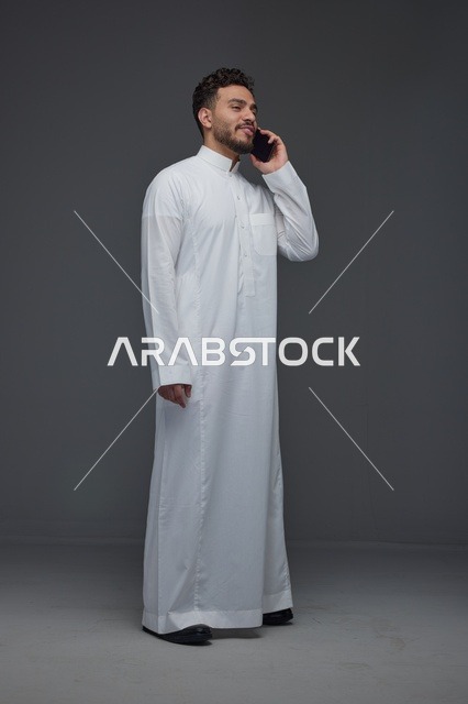 رجل سعودي يرتدي الثوب التقليدي يتحدث عبر الهاتف المحمول