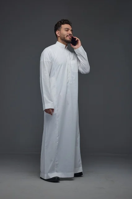 رجل سعودي يرتدي الثوب التقليدي يتحدث عبر الهاتف المحمول