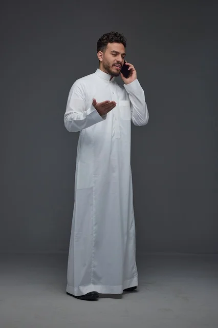 رجل سعودي بالثوب التقليدي يتحدث عبر الهاتف الجوال