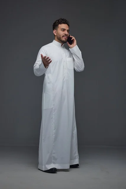 رجل سعودي بالثوب التقليدي يتحدث عبر الهاتف الذكي