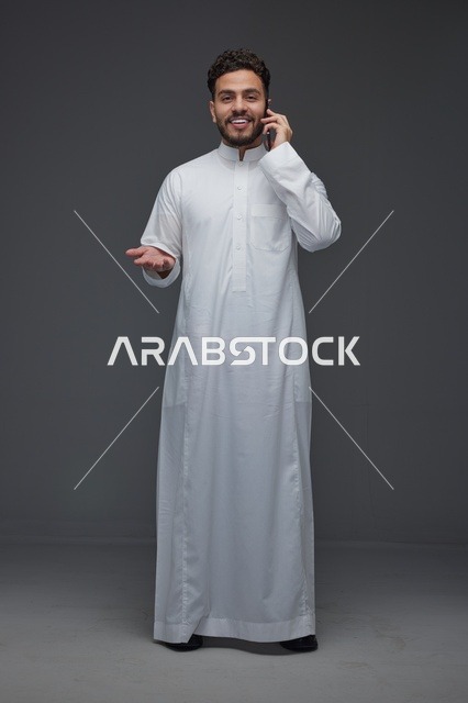 رجل سعودي يجري مكالمة هاتفية مرتديًا الثوب التقليدي