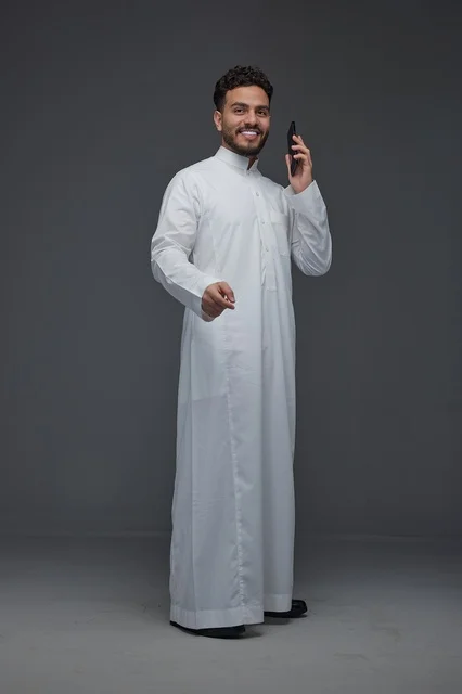 رجل سعودي بالثوب التقليدي يستخدم الهاتف الذكي في استوديو