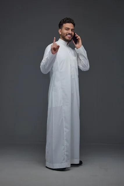 Saudi Man in Traditional Thobe Talking on Smartphone