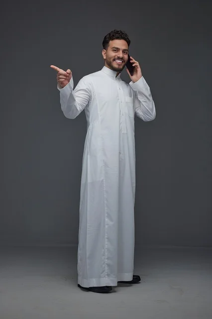 رجل سعودي بالثوب التقليدي يتحدث بالهاتف ويشير للجانب