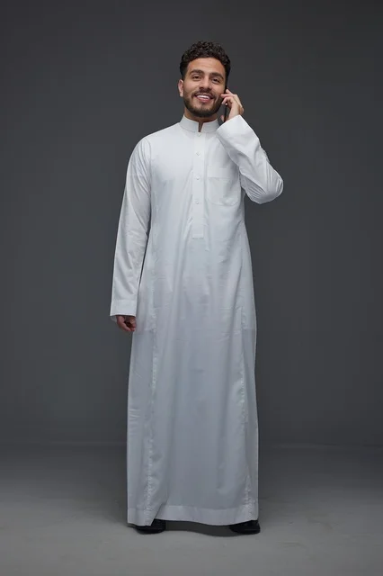 Saudi Man in Traditional White Thobe Making a Phone Call
